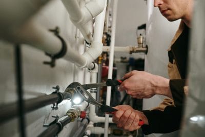 Technician inspecting commercial plumbing pipes in Hawthorne